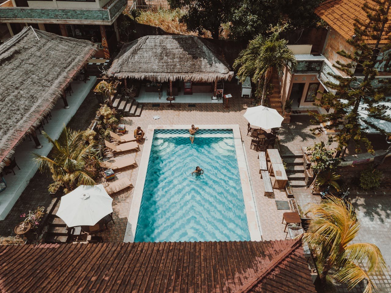 Aerial view of a luxury resort pool surrounded by villas and palm trees.